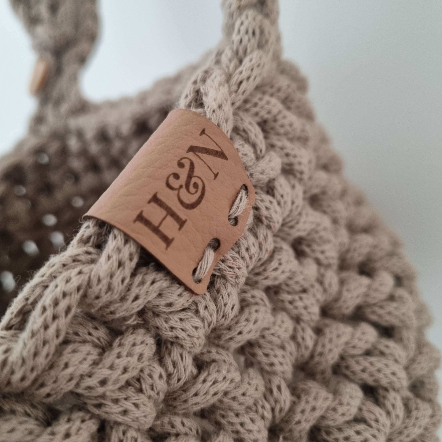 A close up photo of a brown hanging cot basket and its leather tag