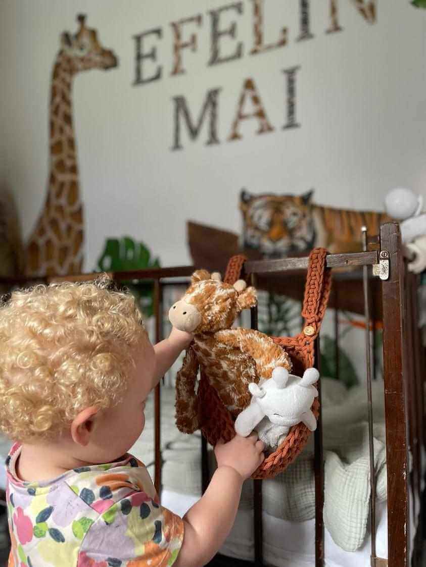 A little girl is pictured taking her toys out of a handmade cot basket