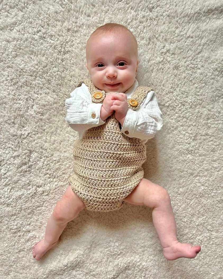 Sweet baby wearing a crocheted overall paired with a white shirt, embodying warmth and style in a lovely ensemble.