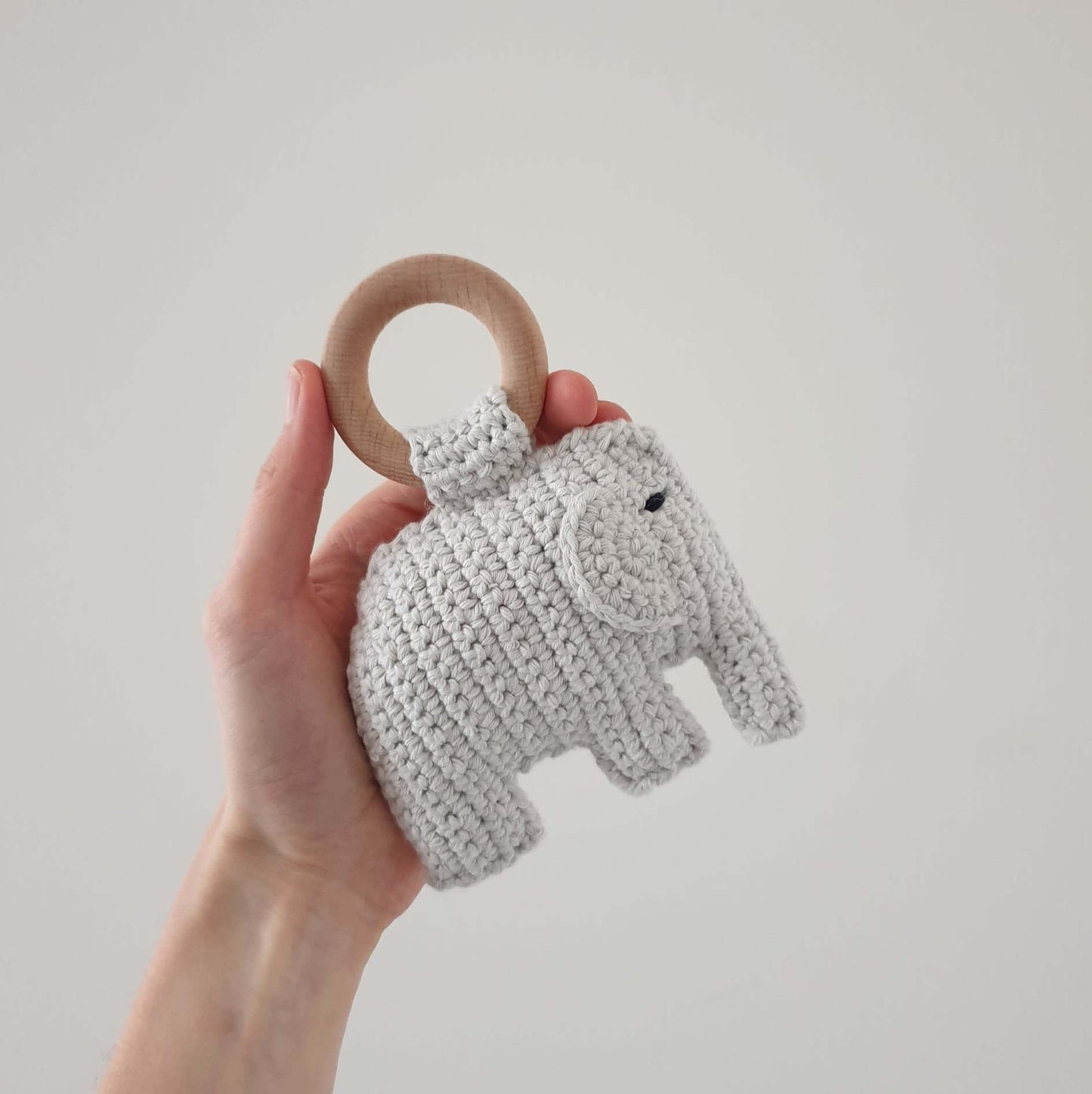 A hand holds a whimsical crocheted Elephant rattle, showcasing its vibrant colors and perfect size for tiny hands.