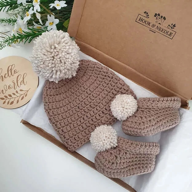 Baby Hat & Boots Set - Brown Pom Pom in a gift box with pom pom details and floral decorations.