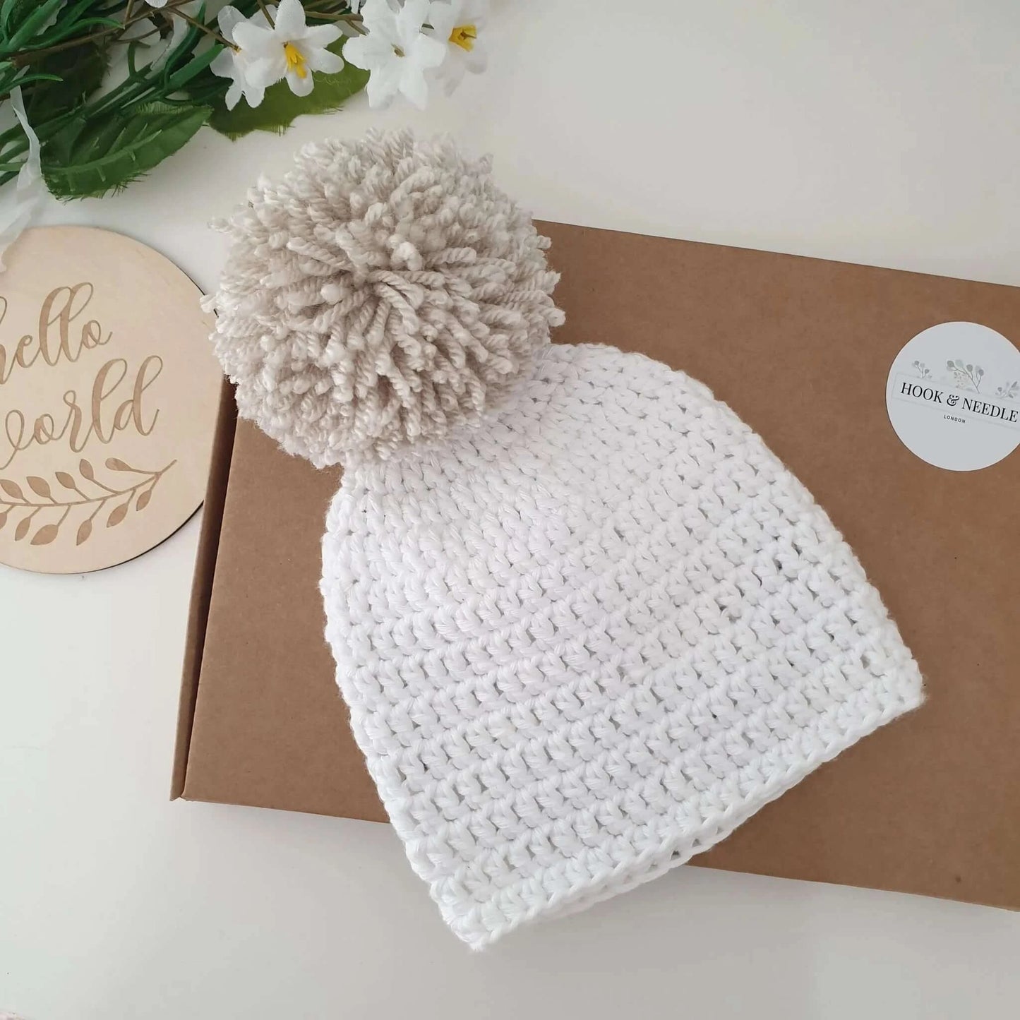 A cozy white crochet hat featuring a playful pom pom on top, perfect for keeping warm and stylish.