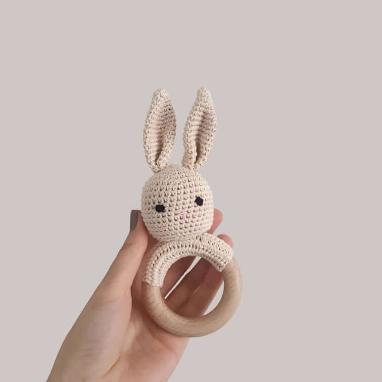 A hand displays a delightful crocheted bunny rattle, emphasizing its playful design and soft texture for babies.