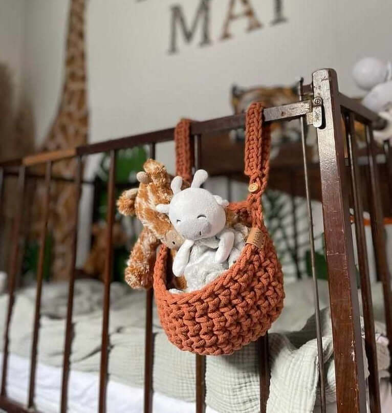 Teddy bears are suspended from a handmade cot basket, creating a whimsical touch in the nursery decor