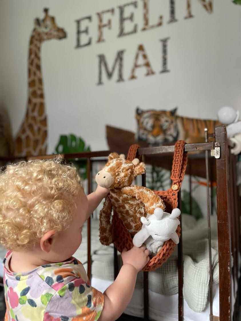 A little girl is pictured taking her toys out of a handmade cot basket