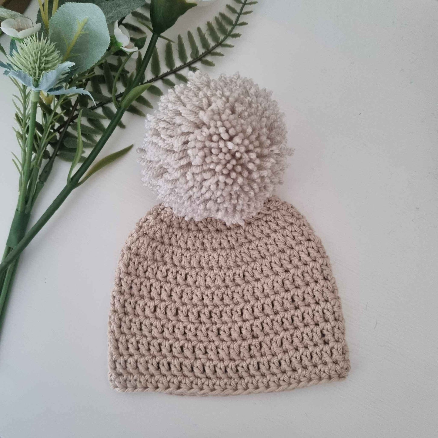  A lovely stone crochet hat topped with a fluffy pom pom, combining warmth and style for the perfect winter accessory.