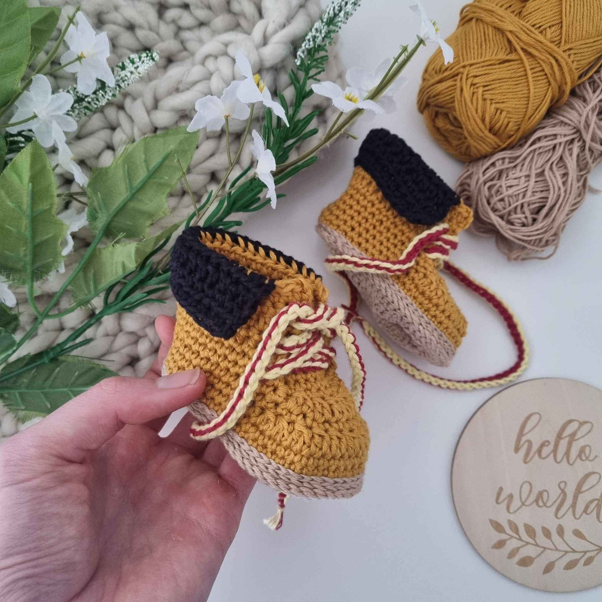 Cute crocheted timberland baby shoes displayed alongside a vibrant yarn ball, showcasing a charming handmade touch for infants.