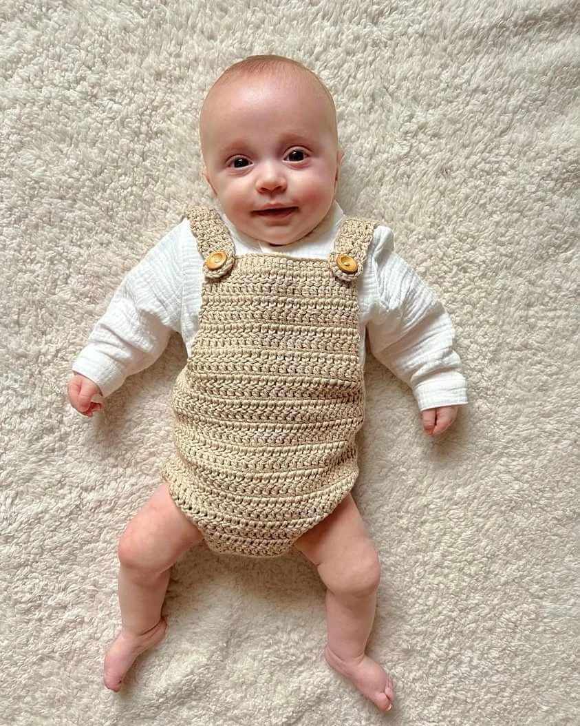 Adorable baby dressed in a crocheted romper and white shirt, radiating cuteness and comfort in this delightful outfit.