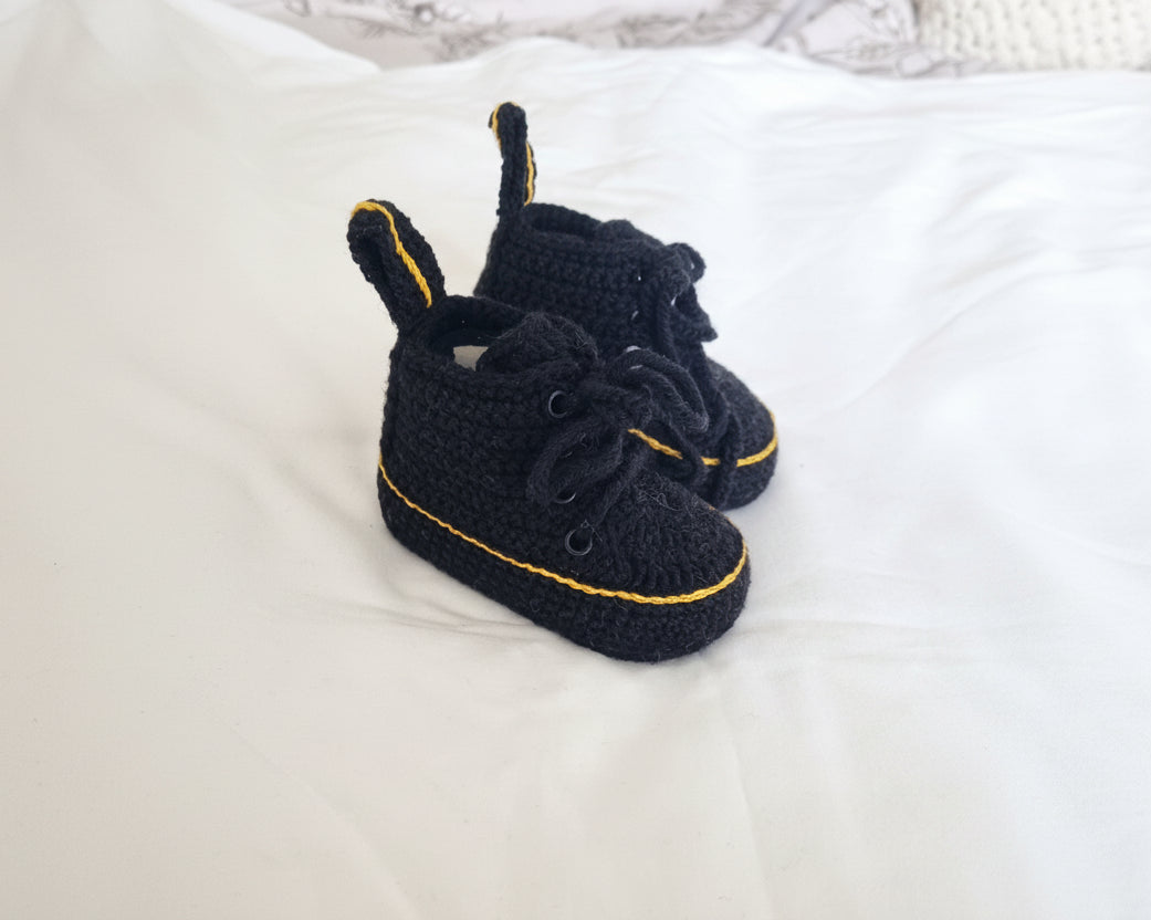 Pair of black shoes with yellow accents on a white surface