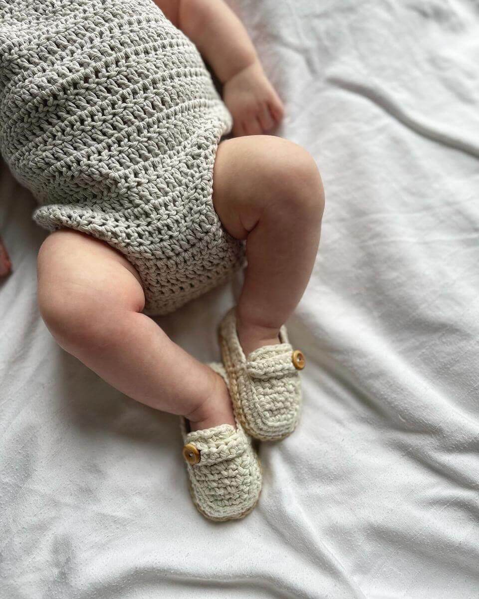 A sweet baby lying on a bed, showcasing their lovely crocheted loafers, perfect for tiny feet and cozy moments.