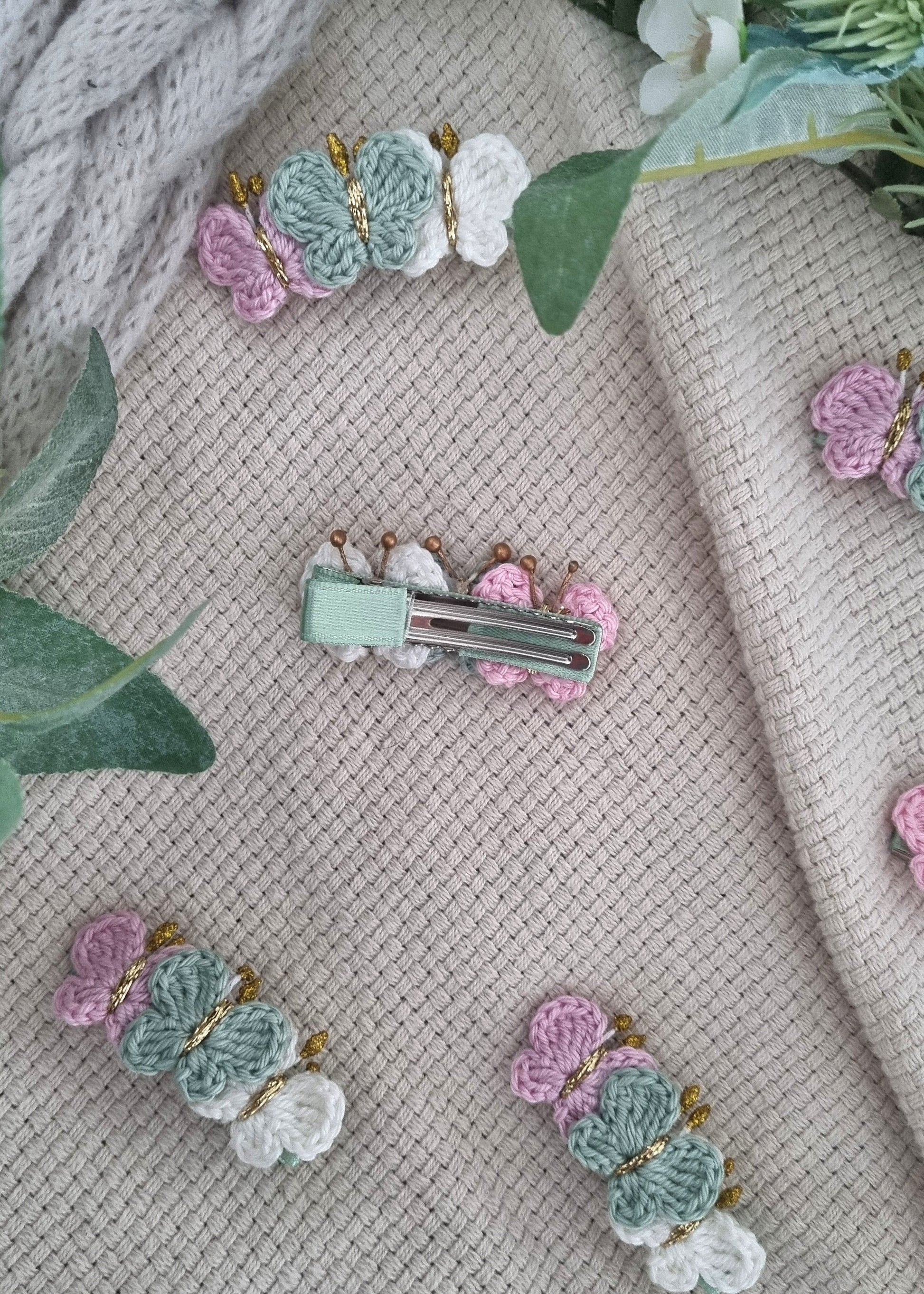 Decorative hair clips with floral designs on a textured fabric background