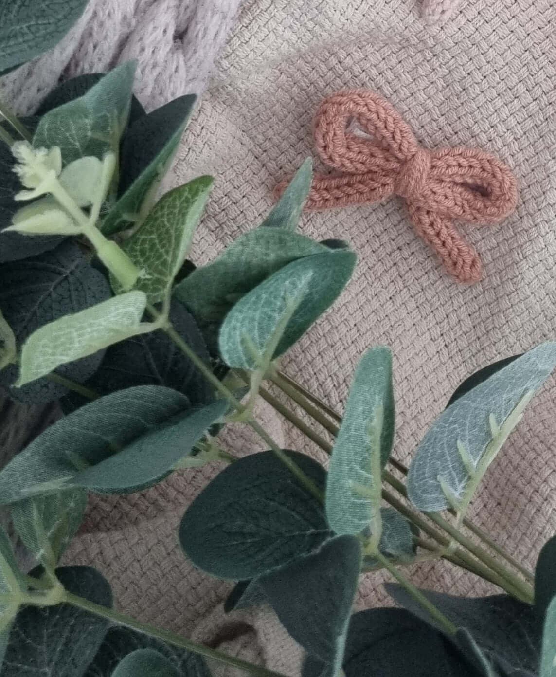 Handmade crochet bow hair clips in soft yarn, surrounded by greenery and textured fabric, perfect for little outfits.