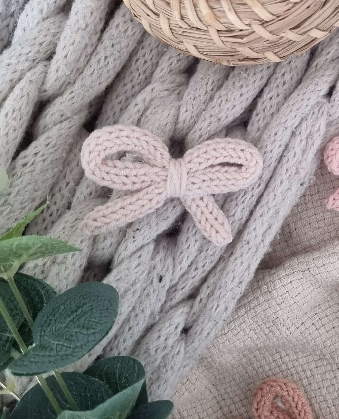 handmade crochet bow hair clips resting on soft knit fabric, showcasing neutral tones and delicate design.