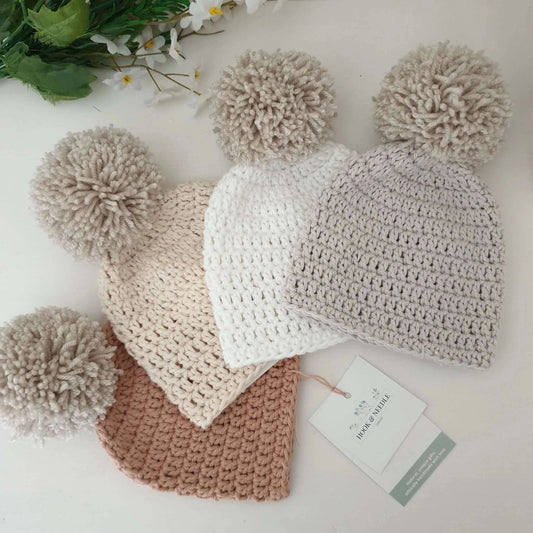 A selection of delightful neutral crochet hats with a cheerful pom pom on top, perfect for staying warm while looking fashionable in winter.