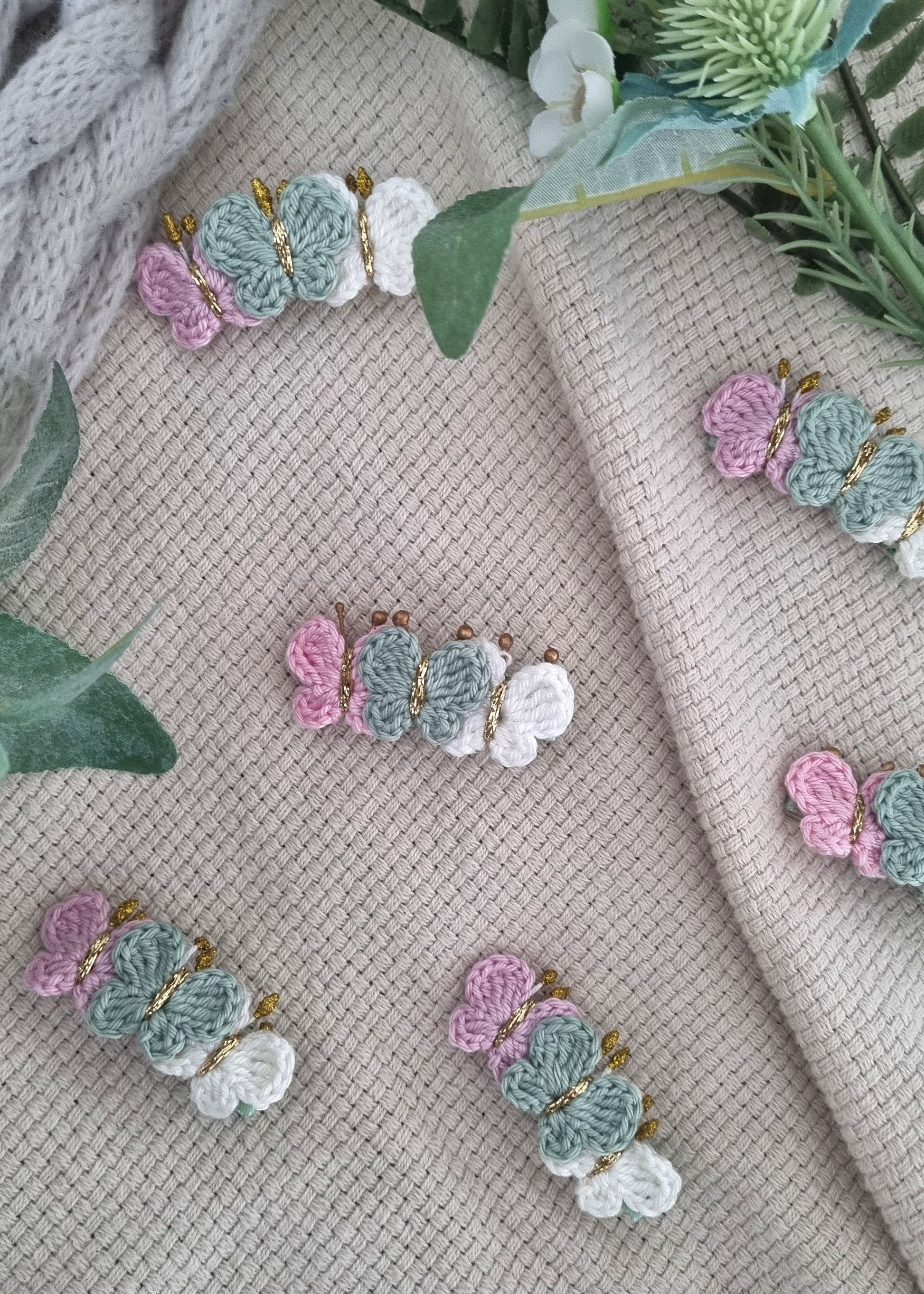 Pastel floral earrings on a textured fabric background with green leaves.