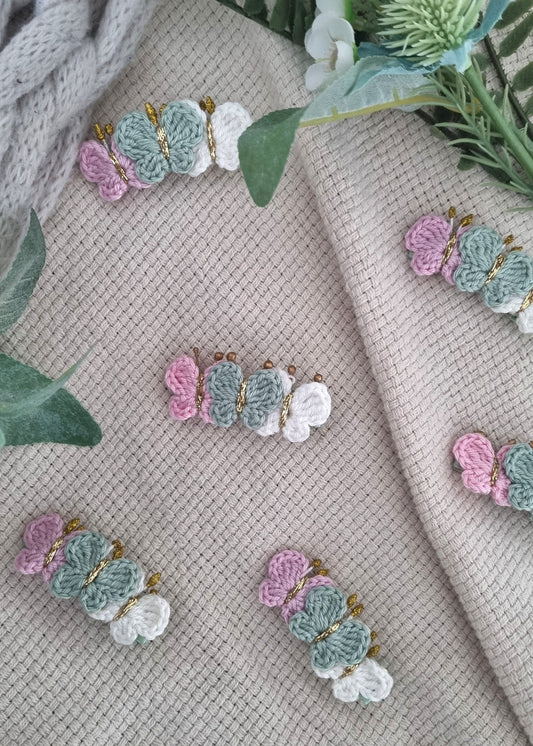 Pastel floral earrings on a textured fabric background with green leaves.