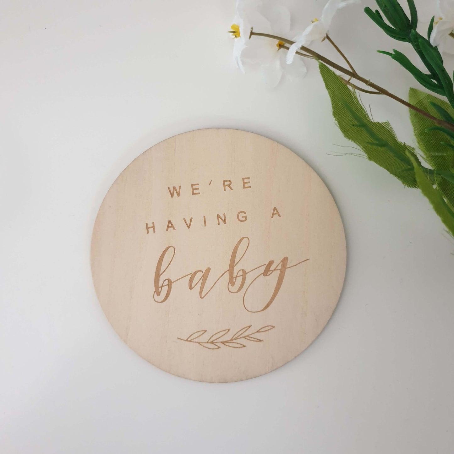 Wooden disk with the words "were having a baby"