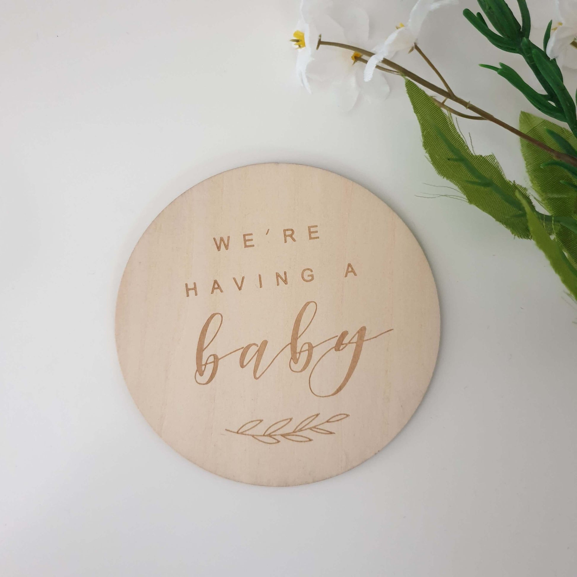 Wooden disk with the words "were having a baby"